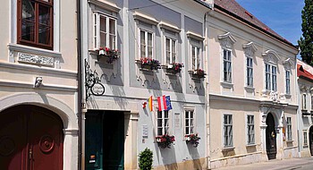 Kleines, blaues barockes Bürgerhaus mit drei kleinen Fahne an der Front
