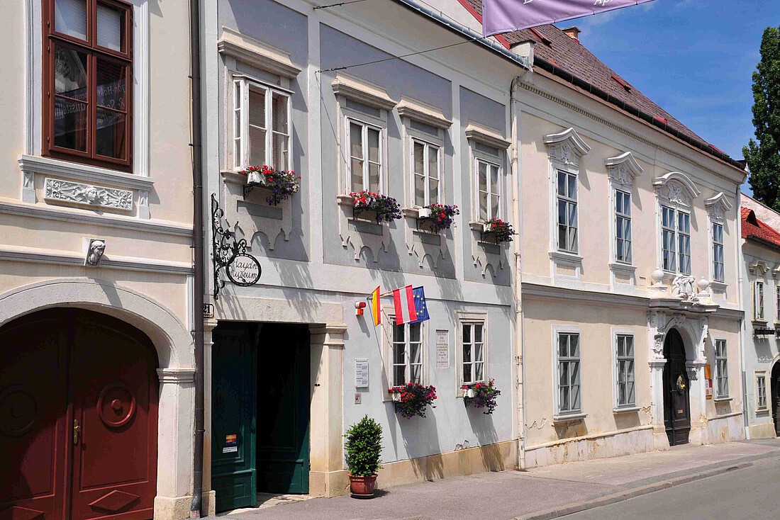 Kleines, blaues barockes Bürgerhaus mit drei kleinen Fahne an der Front