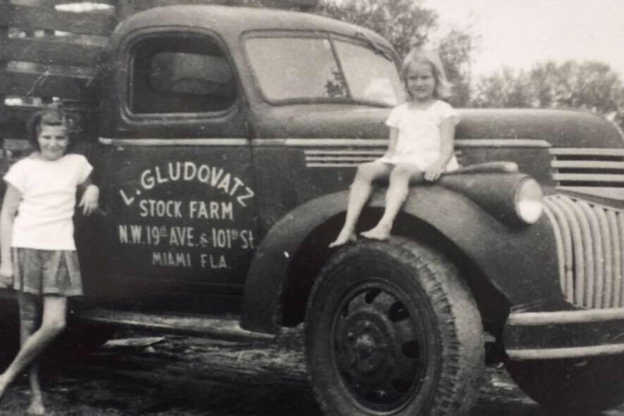 Schwarz-weiß-Fotografie aus den 1950er Jahren. Zwei Mädchen sitzen auf einem Lastwagen