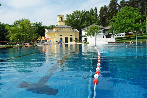 Schwimmbecken und gelbes historisches Gebäude in einem Park