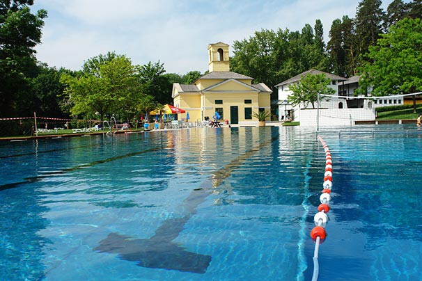 Schwimmbecken und gelbes historisches Gebäude in einem Park