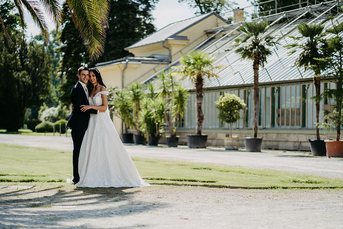 Brautpaar stehend vor der Orangerie im Schlosspark