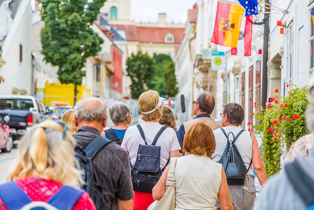 Eine Touristengruppe geht durch eine historische Straße mit barocken Häusern