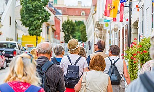 Eine Touristengruppe geht durch eine historische Straße mit barocken Häusern