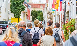 Eine Touristengruppe geht durch eine historische Straße mit barocken Häusern