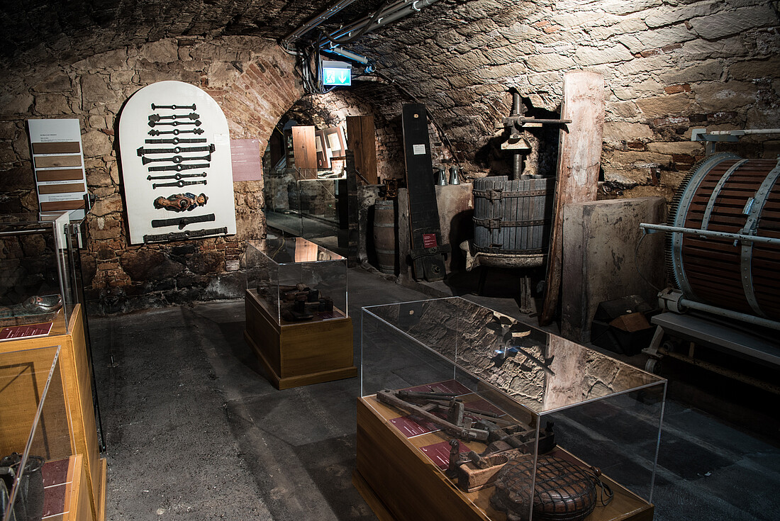 Alter Gewölbekeller mit historischer Weinpresse und Werkzeug