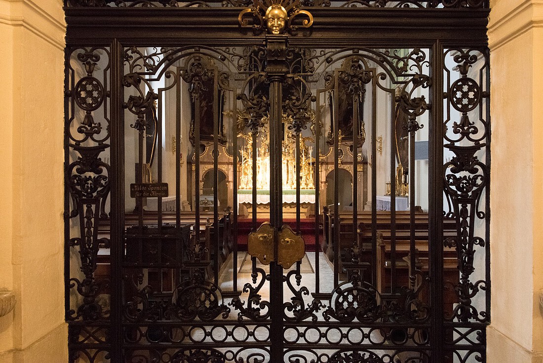 Kunstvolles schmiedeeisernes Gittertor mit Blick in den barocken Innenraum einer kleinen Kirche