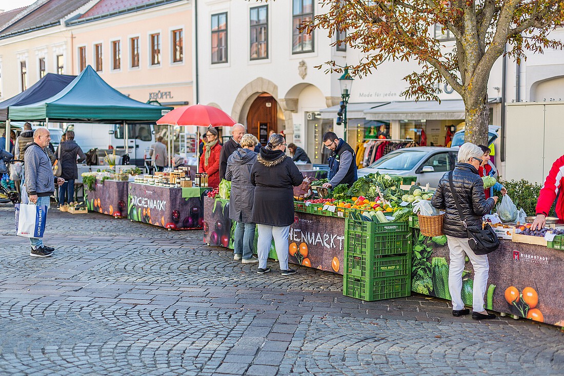 Eine Reihe von Marktständen mit Obst und Gemüse und Kunden