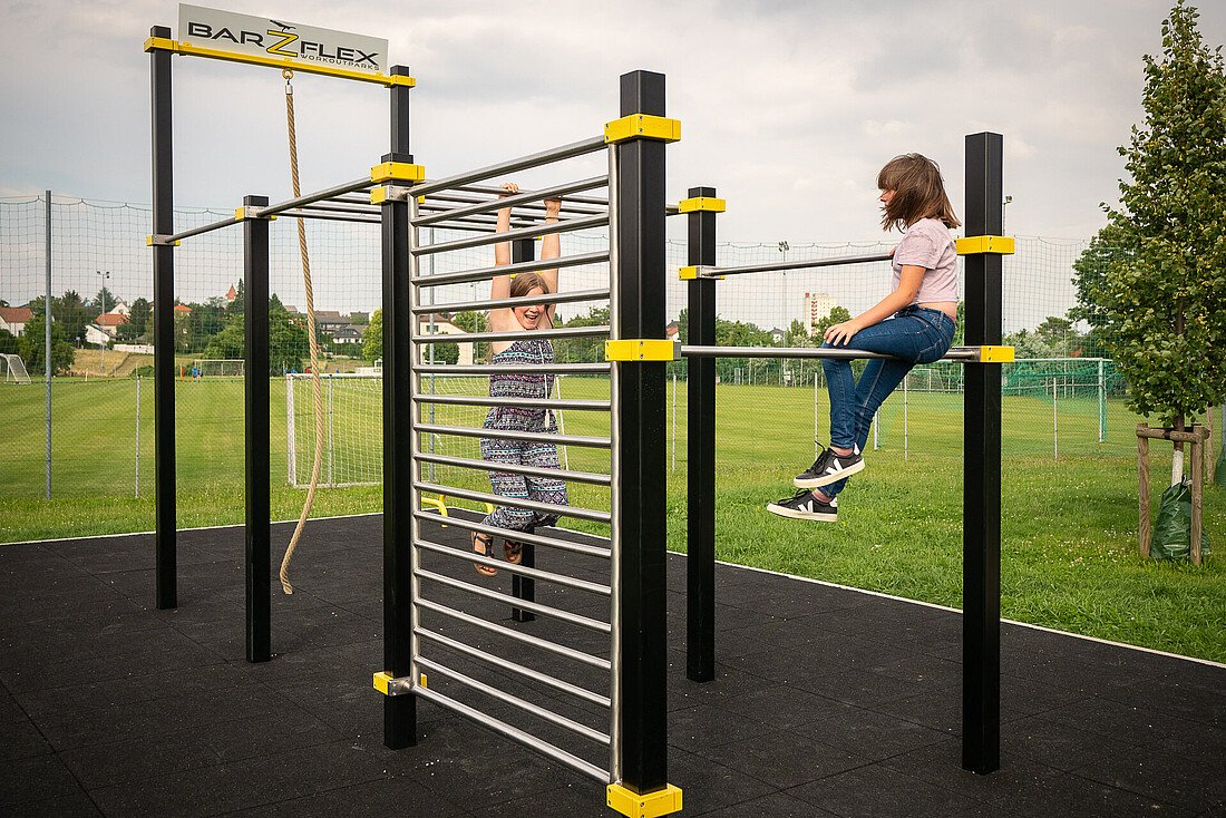 Zwei Mädchen auf einem Klettergerüst auf einem Spielplatz.