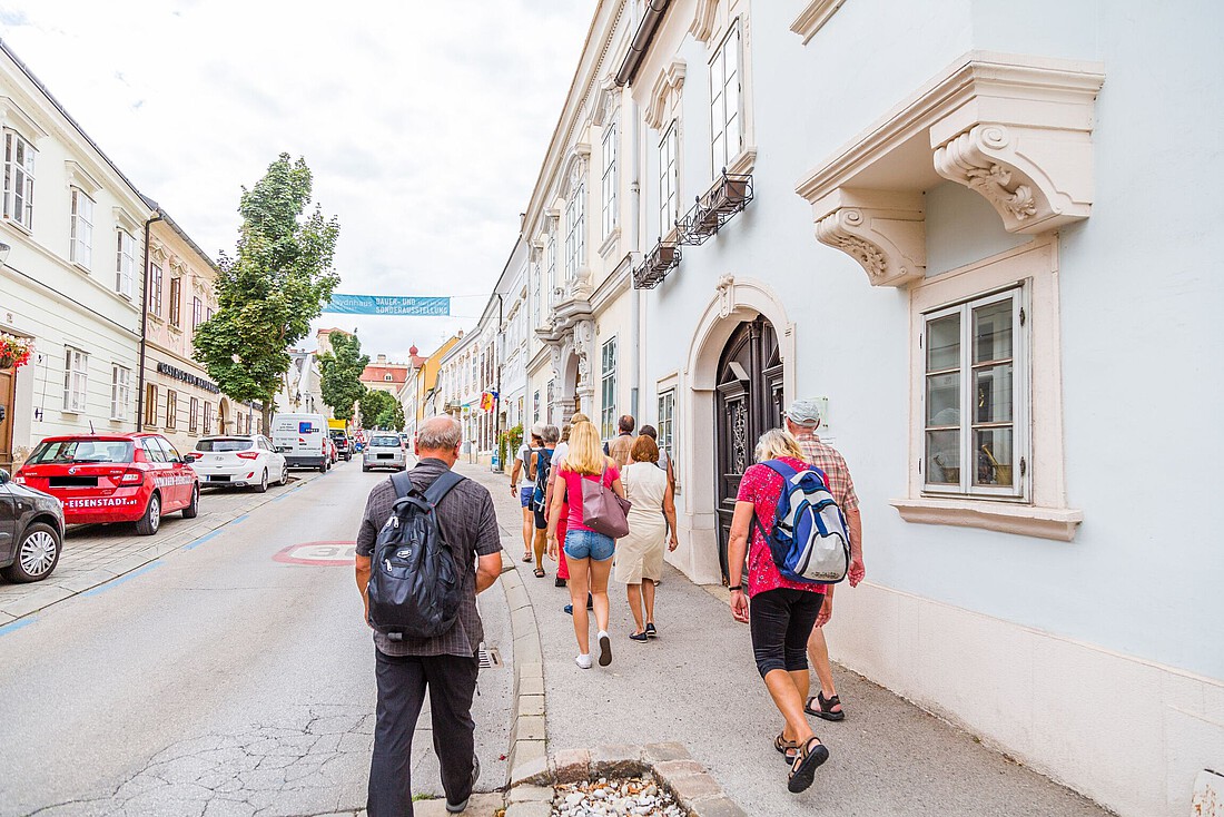 Eine Touristengruppe geht durch eine Straße mit barocken Bürgerhäusern
