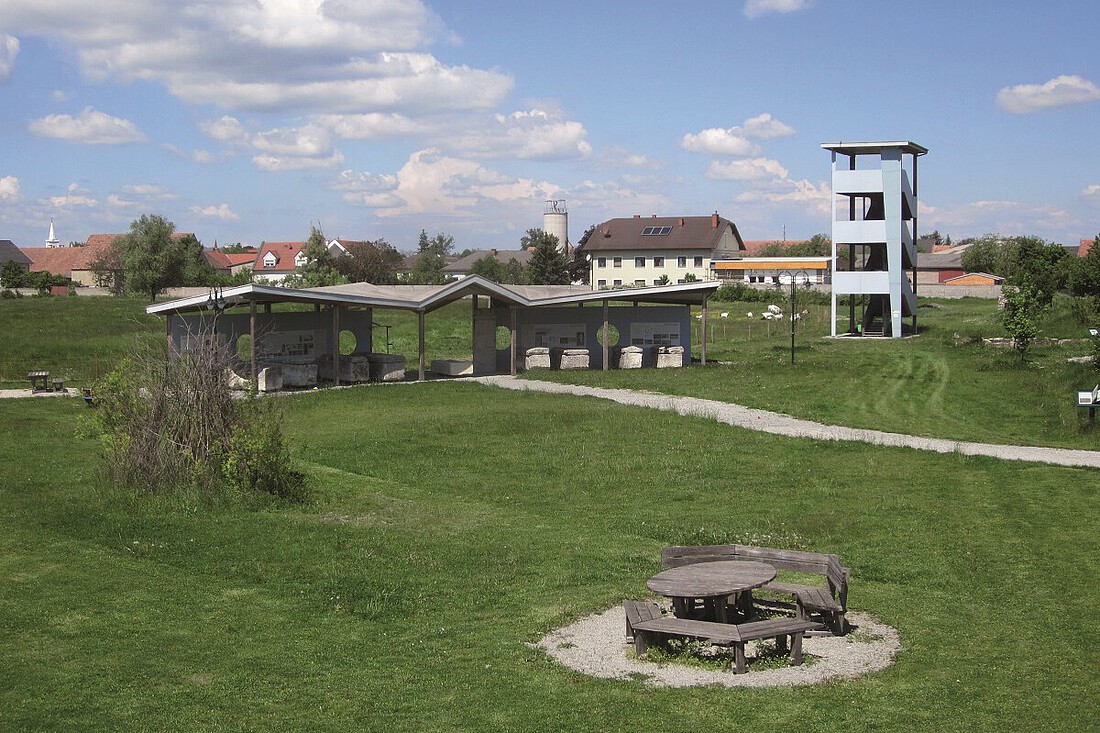 Aussichtsturm aus Metall und Informationstafeln auf einer Wiese