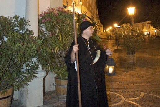 Mann in historischem Nachtwächerkostüm auf einer Straße am Abend