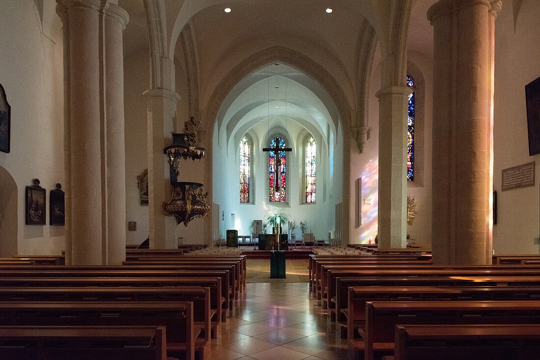 Gotische Kirche mit Kirchenbänken, barocker Kanzel und bunten Kirchenfenstern