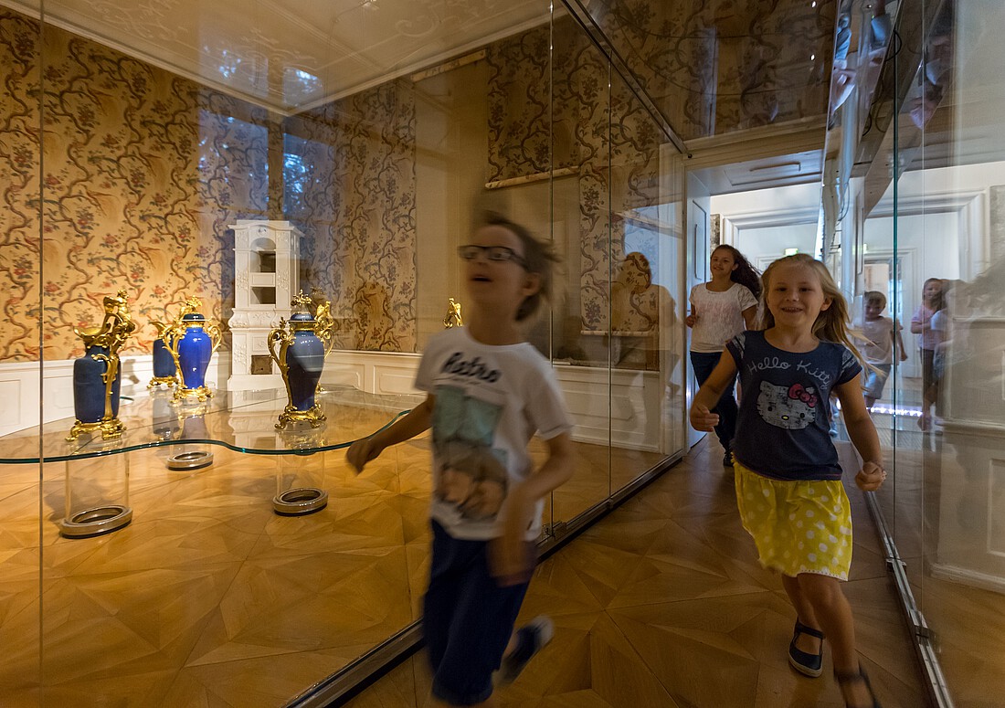 Drei Kinder laufen durch einen Austellungsraum in einem Schloss