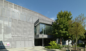 Das Gebäude des Kulturzentrums von aussen mit Vorplatz und grünem Baum