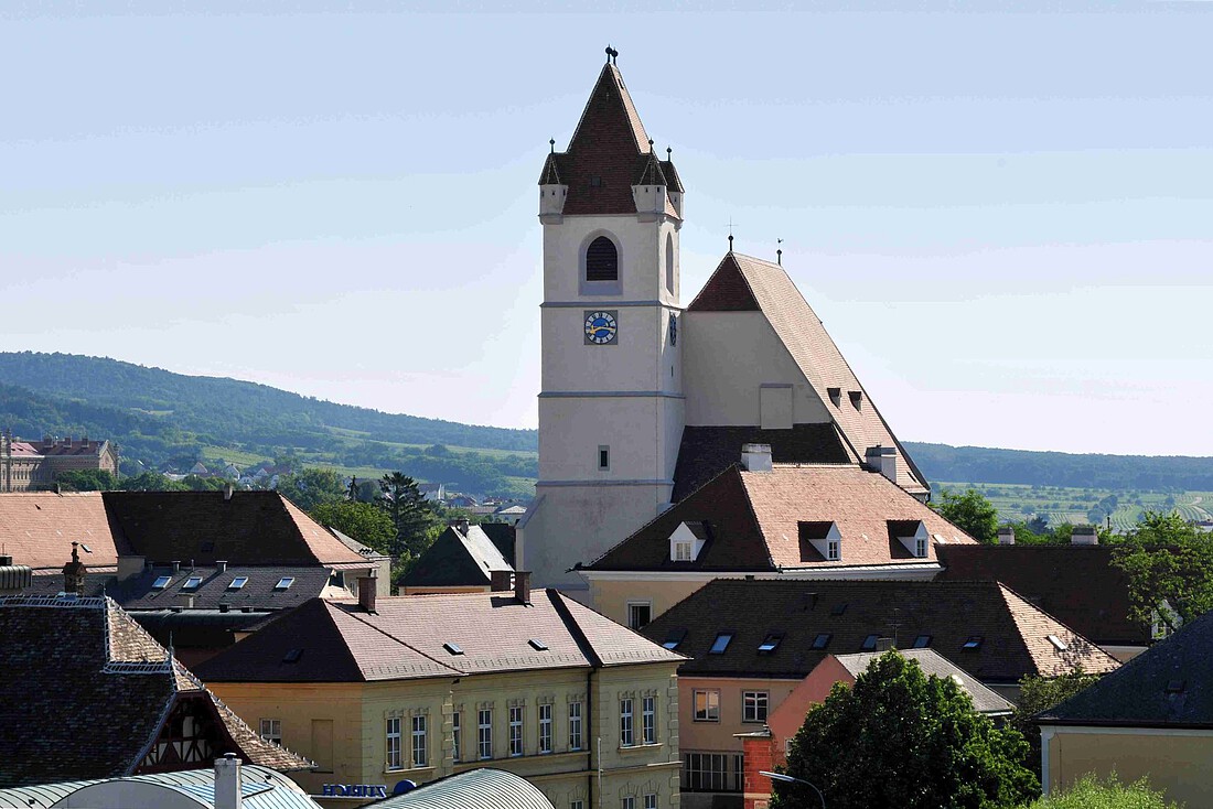 Große Hallenkirche mit hohem Turm und kleineren Häusern im Vordergrund