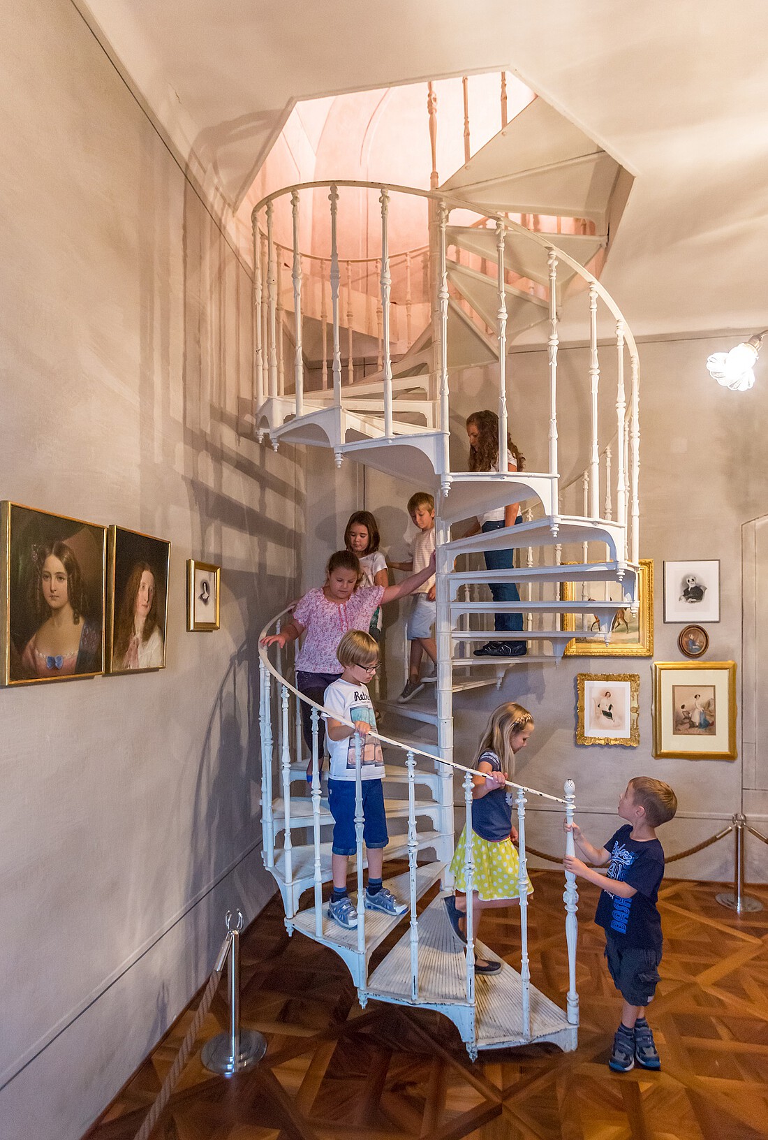 Sieben Kinder auf einer Wendeltreppe in einem Museum
