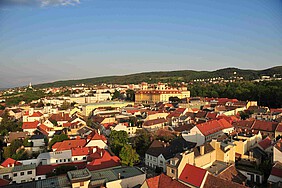 Luftaufnahme einer Stadt mit barockem, gelben Schloss.