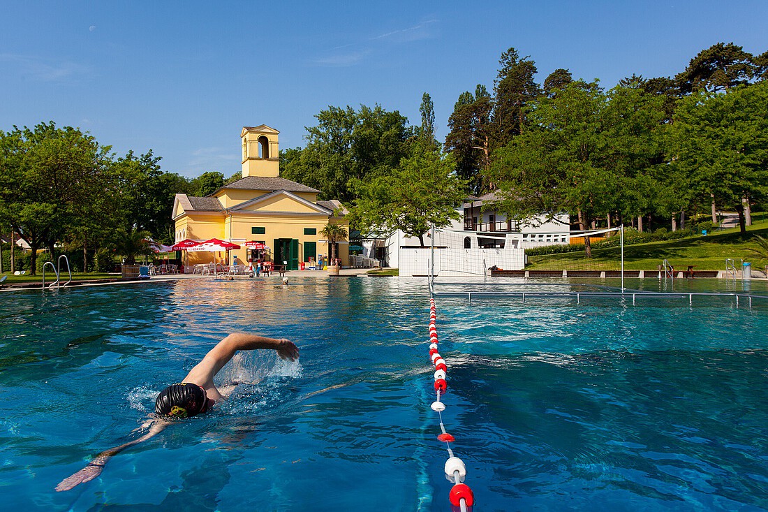 Mann mit Badehaube schwimmt in einem Becken in einem Freibad