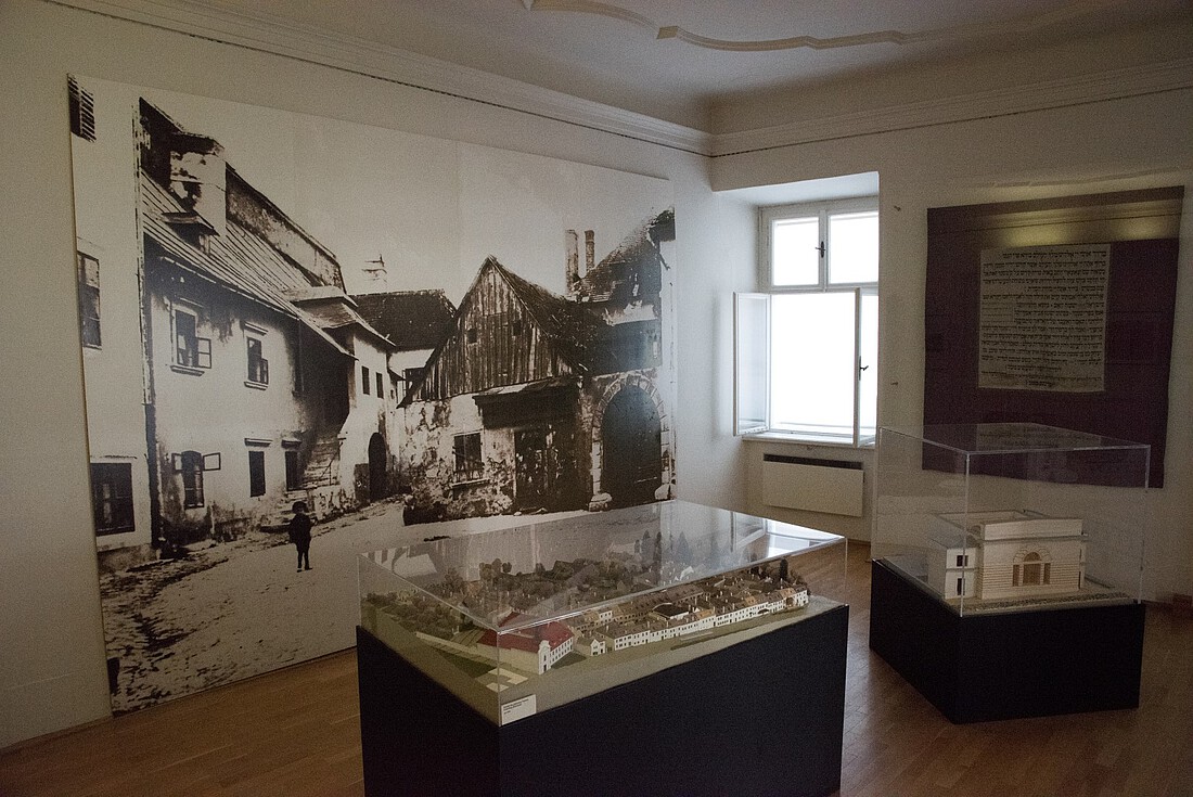 Museumsraum mit Ausstellungsvitrine und großem Bild an der Wand